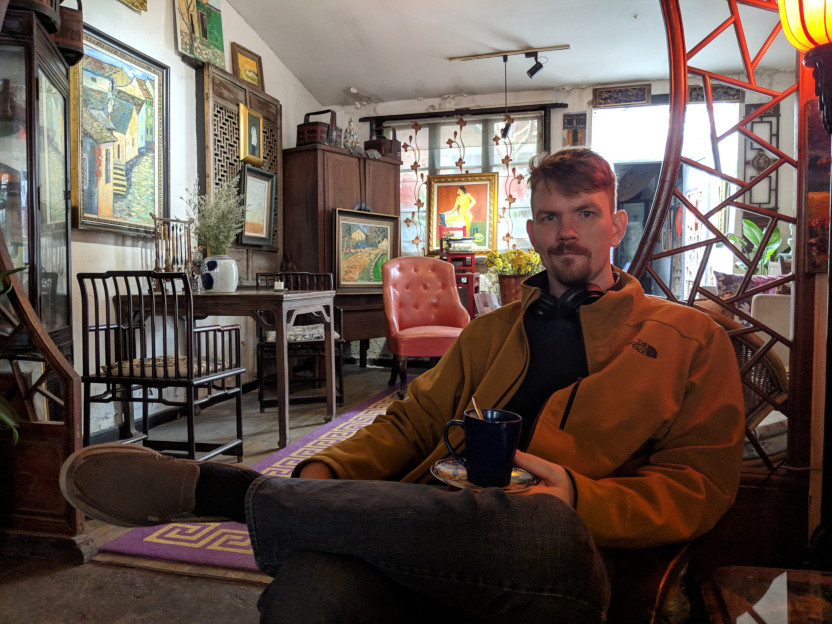 Jonathan Hawley-Peters reclining with a coffee cup in a cafe in China